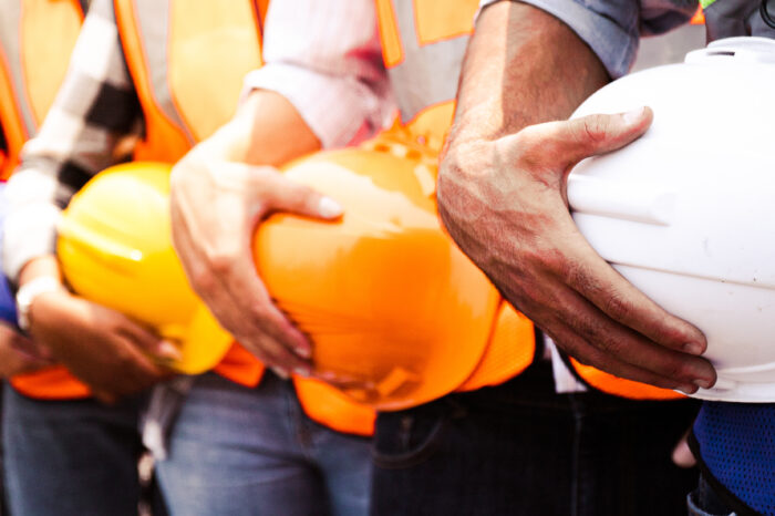 Engineer team holding hardhat standing in row ready for work.Wor